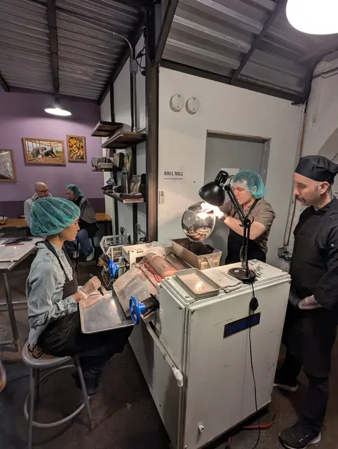An instructor watches as Emily and Chris make chocolate